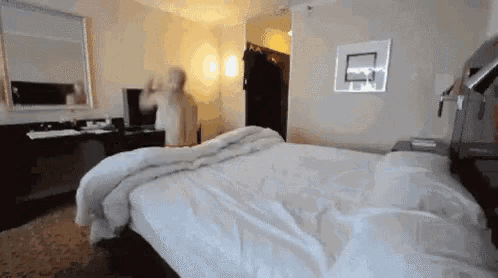 Homem pulando na cama macia com uma cambalhota