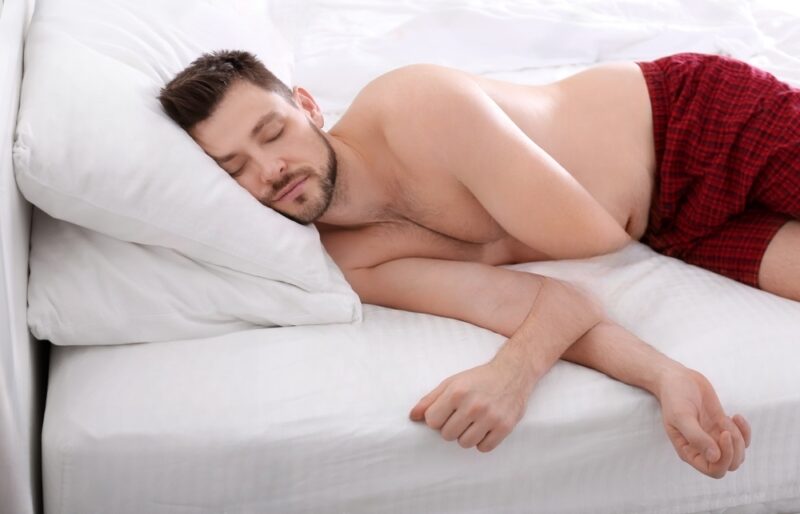 Homem dormindo em dois travesseiros de maneira inadequada